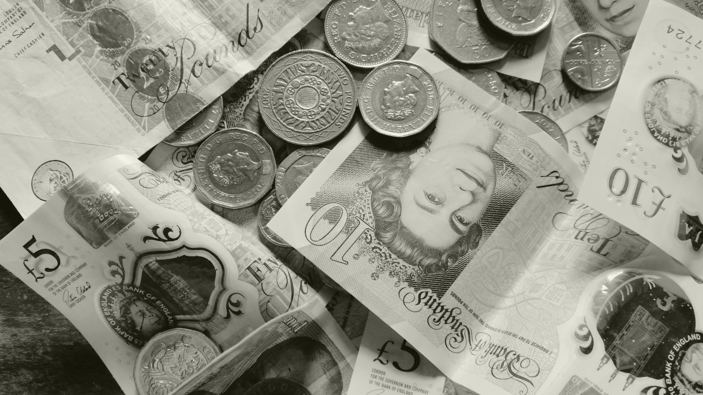 British pound coins and banknotes scattered, representing financial costs and spending in UK healthcare.
