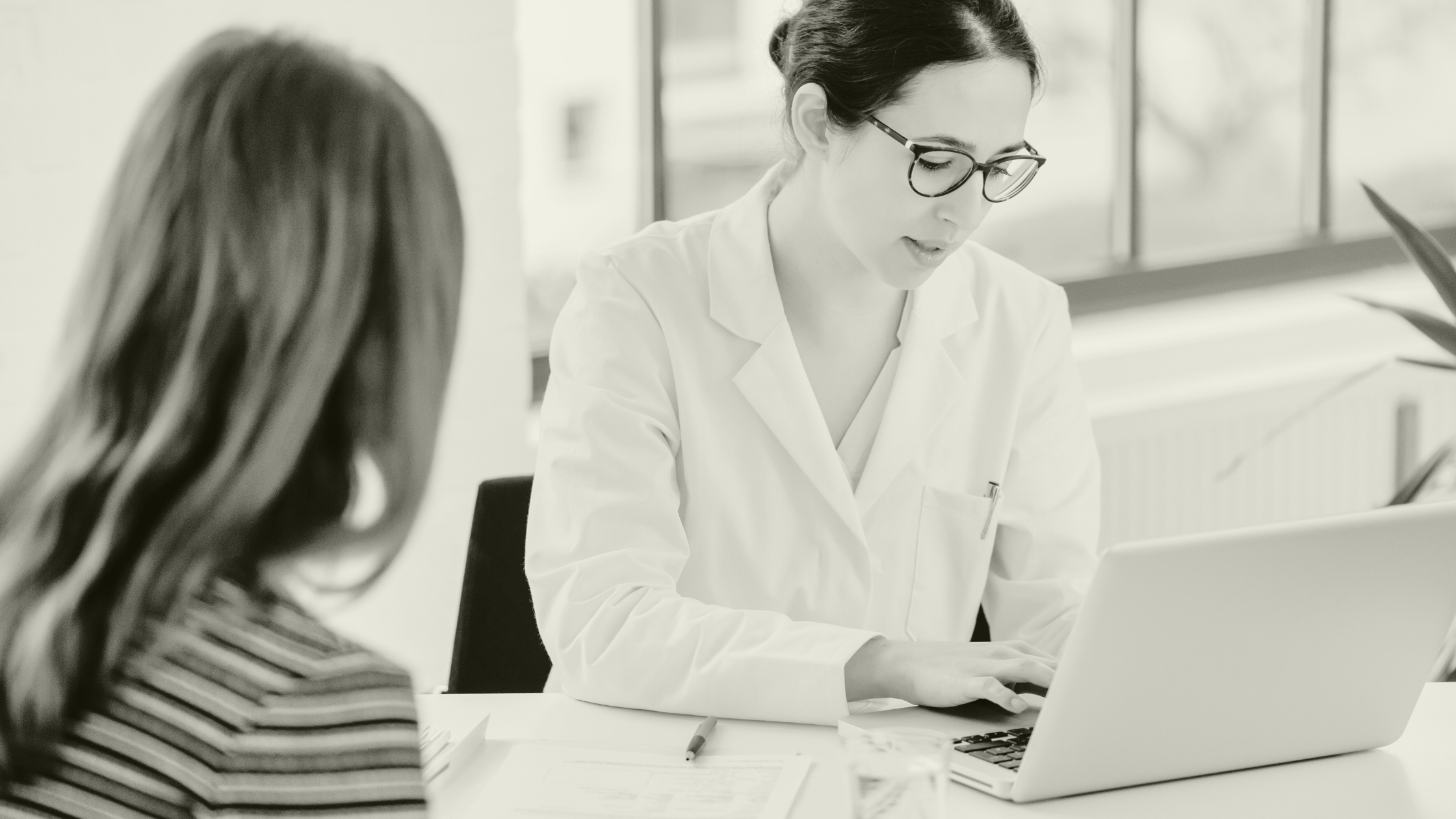 Locum GP reviewing patient notes during a consultation, supporting continuity of care in a primary care setting