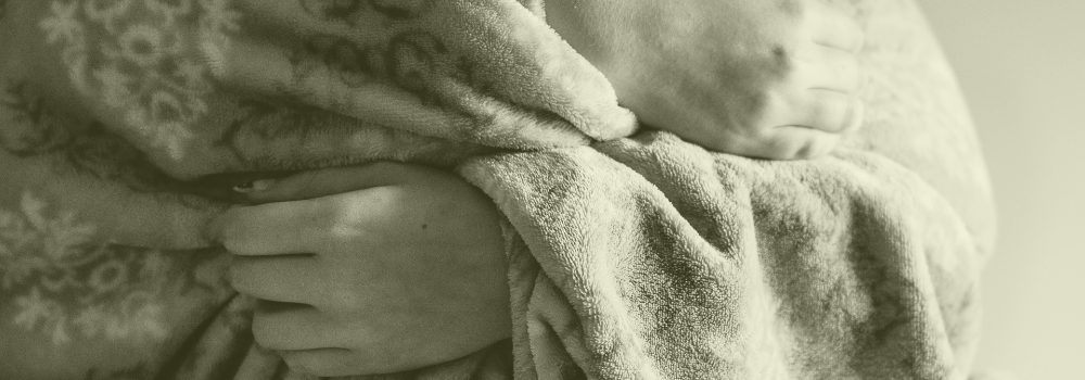 Hands holding a blanket symbolising winter pressures in healthcare, representing the need for proactive primary care staffing support with Vela Medical Group.