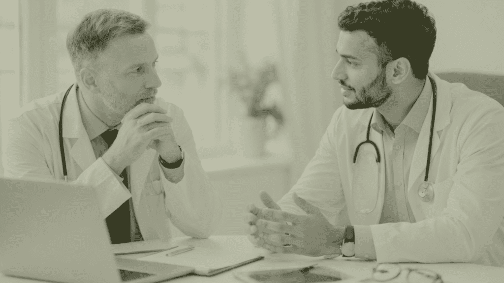 Two General Practitioners in a UK Primary Care practice discussing GP partnership, succession planning and workforce leadership at a practice meeting