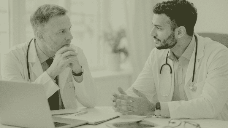 Two General Practitioners in a UK Primary Care practice discussing GP partnership, succession planning and workforce leadership at a practice meeting