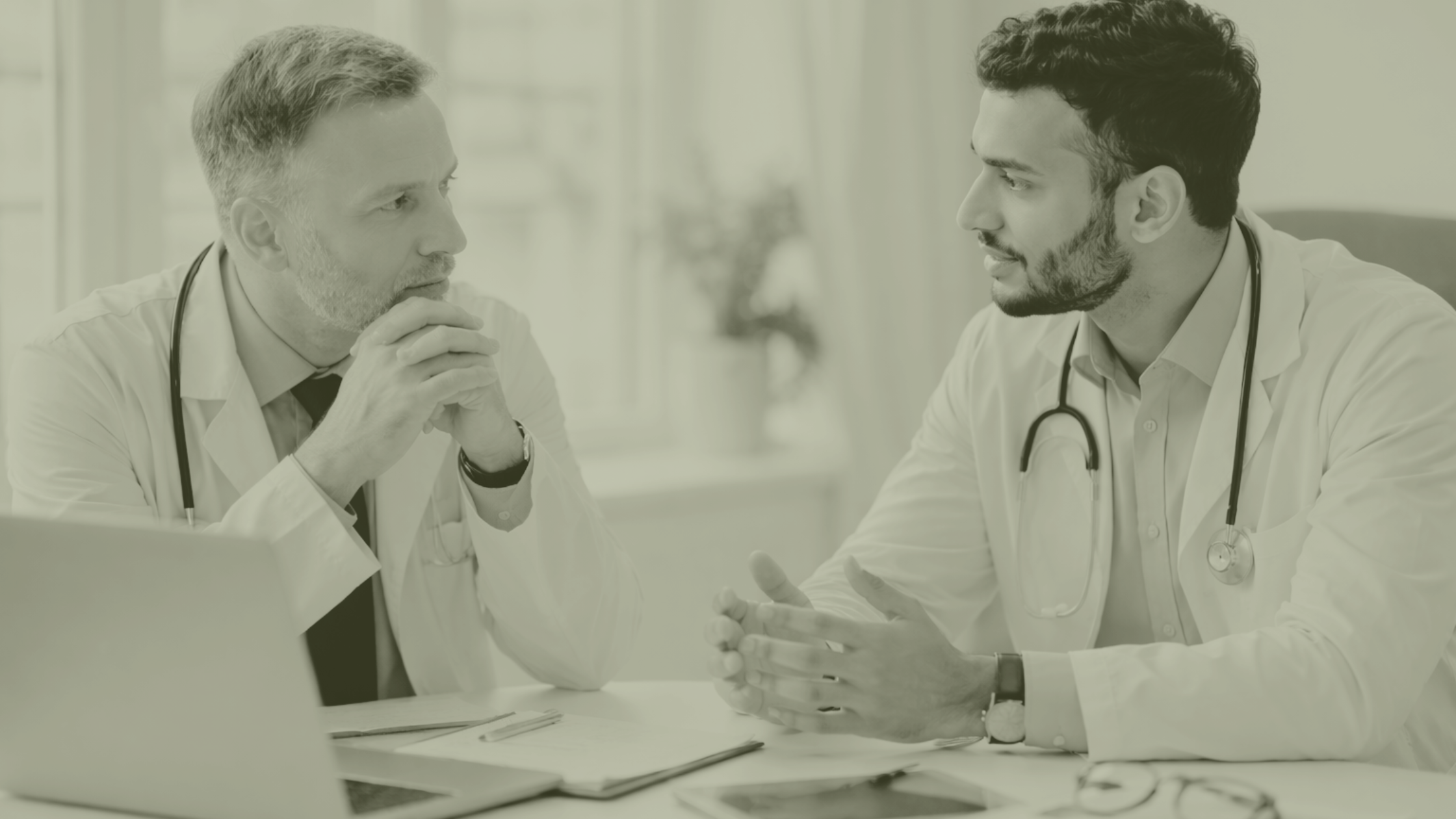 Two General Practitioners in a UK Primary Care practice discussing GP partnership, succession planning and workforce leadership at a practice meeting